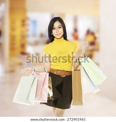 Full body asian woman hold shopping bags with blurred mall background