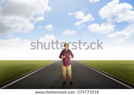 Traveler man with backpack posing on empty road
