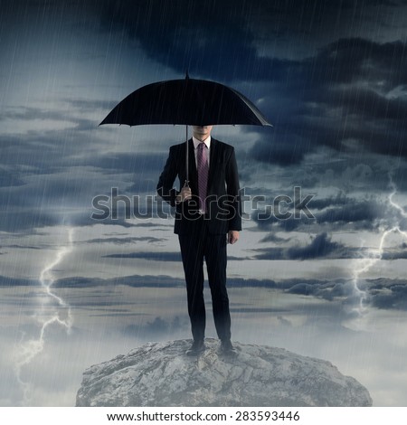 Man holding umbrella standing on the rock with thunder storm weather. Business depression concept