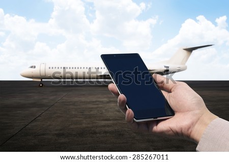 Hand holding cellphone with blank screen on the airport. You can put your design on the cellphone