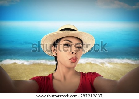 Woman take selfie with duck face on the beach. Vacation concept