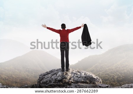 Asian business man standing on the top of mountain, raise hand and open his suit