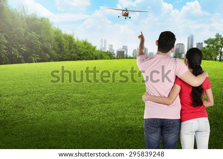 Asian couple pointing propeller plane on the city park
