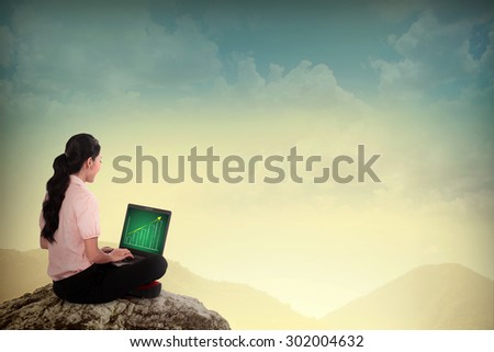 Asian business woman using a laptop on top of the mountain
