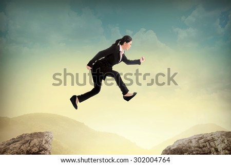 Business woman jump to another peak of mountain. Business challenge concept