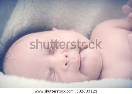 Peaceful baby lying on a bed while sleeping in a bright room over white sheet