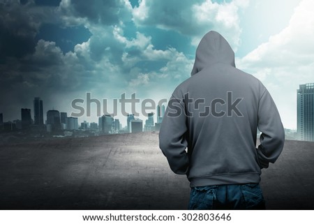 Faceless man in hood on the rooftop with city background