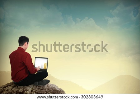 Asian business man working with laptop on the top of the mountain