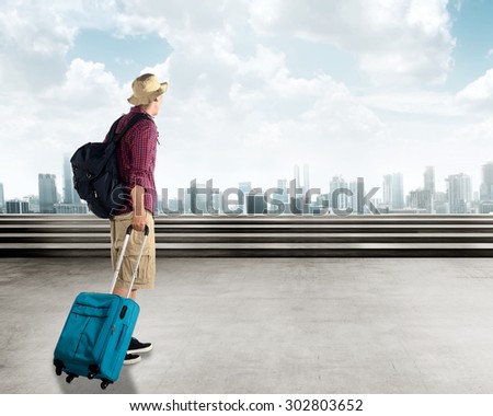 Young asian traveler walking in the city carry a suitcase