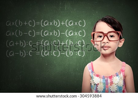 little schoolgirl with green chalkboard with math formulas