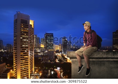 Male tourist sitting on the building rooftop at night time