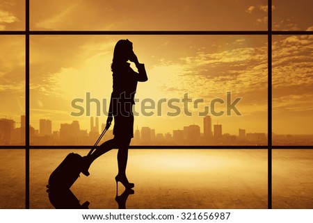 Silhouette of business woman walking with suitcase over city background. Business travel concept