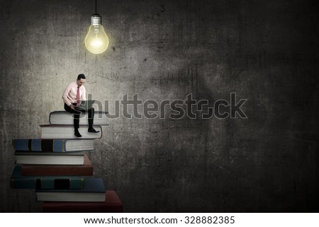 Asian business person working with laptop sit on top of book. Idea and knowledge concept