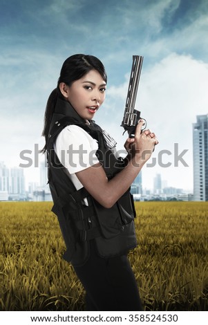 Beautiful police woman holding gun ready to fire