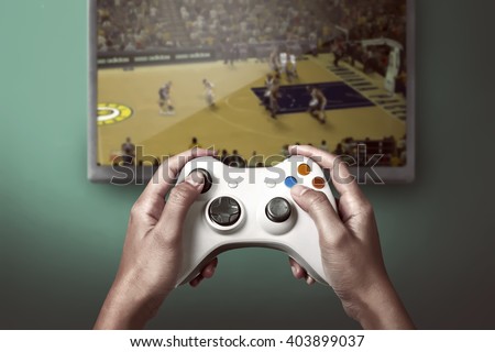 Hand holding game console controller playing sport game on the television