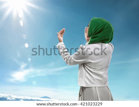 Back view of muslim woman praying wearing hijab