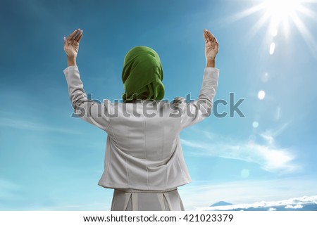 Back view of muslim woman praying wearing hijab