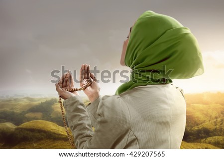 Young muslim woman holding prayer beads standing on mountain