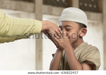 Asian muslim child kissing a hand from an old people in the mosque