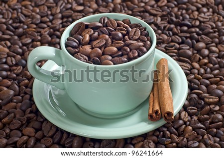 Coffee bean in the coffee cup served with cinnamon shot with coffee bean background
