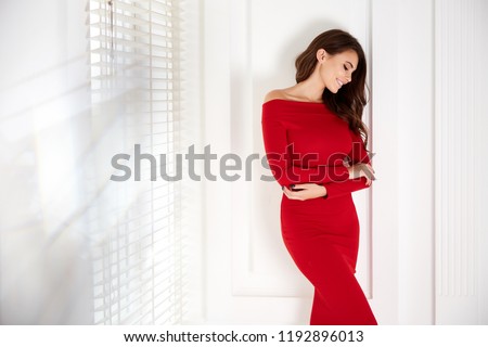 Beautiful sexy young business woman brunette hair with evening make-up wearing a red skinny dress and high-heeled shoes  business clothes for meetings and walks fall collection perfect body shape.
