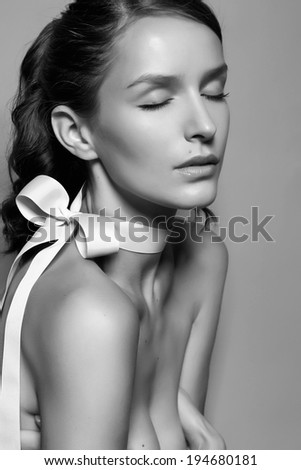 Black and white tender profile fashion portrait of Beautiful gentle young brunette woman with close soft eyes and sensitive mouth wearing silk bow on the neck and right shoulder