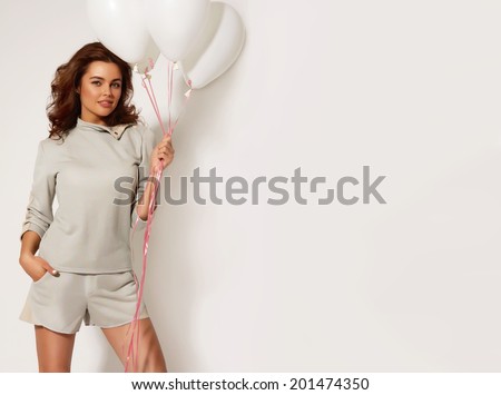 Beautiful smiling girl holding white balloons on a white background at the studio