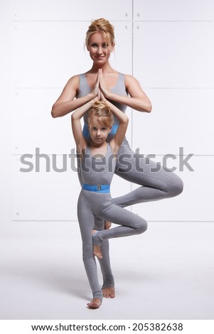 Mother and daughter doing yoga exercise, fitness, gym wearing the same comfortable tracksuits, family sports, sports paired