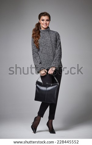 Beautiful young business woman with evening make-up wearing a skirt to the knee and a silk blouse with lace long sleeves and high-heeled shoes and a small black handbag, business clothes for meetings