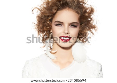 Beautiful young girl with a bright evening make-up of shiny red lipstick long fluffy eyelashes blond curly hair holding snowflake near the face winter knitted sweater New Year Christmas joy happiness