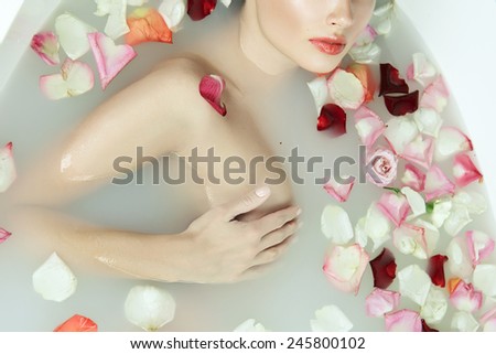 Beautiful young sexy girl with dark hair wet, evening makeup, takes bath with milk tan perfect skin in romantic atmosphere, beauty cosmetic salon and spa for woman at Valentine\'s Day