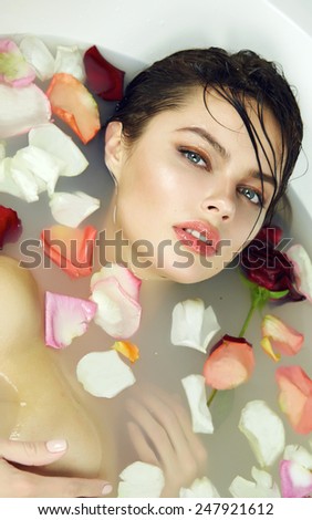 Beautiful young sexy girl with dark hair wet, evening makeup, takes bath with milk tan perfect farfor skin in romantic atmosphere, beauty cosmetic salon and spa for woman at Valentine\'s Day
