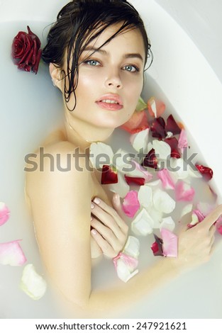 Beautiful young sexy girl with dark hair wet, evening makeup, takes bath with milk tan perfect farfor skin in romantic atmosphere, beauty cosmetic salon and spa for woman at Valentine\'s Day