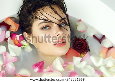 Beautiful young sexy girl with dark hair wet, evening makeup, takes bath with milk tan perfect white skin light tan in romantic atmosphere, beauty cosmetic salon and spa for woman at Valentine\'s Day