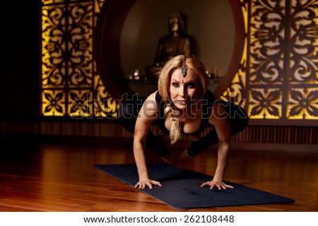 Beautiful young sexy blond girl with a sporty physique slender figure doing yoga exercises  fitness in slinky suit meditates relaxes pilates
