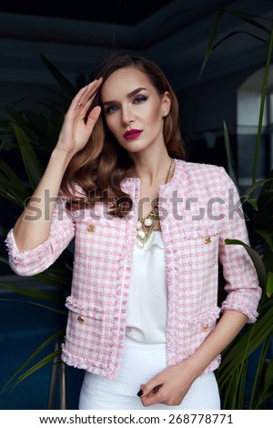 Beautiful stylish young fashion girl with perfect evening make-up with pink lips and green eyes, staying near swimming pool in elegant summer clothes hills, skirt, top and jacket, and golden bijou