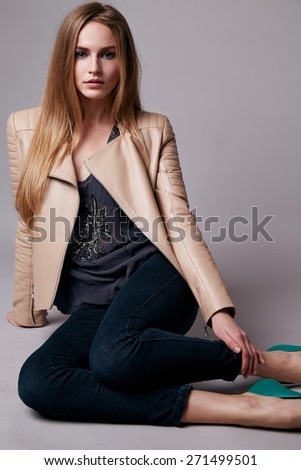Beautiful young teen girl with long blonde hair with natural make-up wearing jeans and jacket Leather and shoes on the floor model with a clothing catalog spring collection
