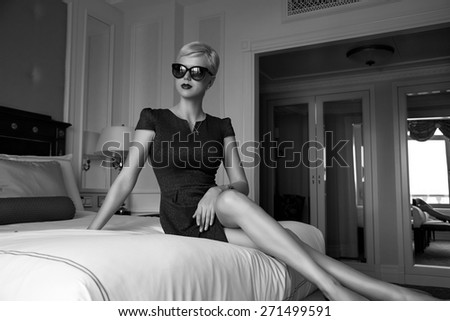 Beautiful young sexy blond woman with short hair sunglasses  makeup business woman reading a rest in a room  in the luxurious interior in stylish clothes collection