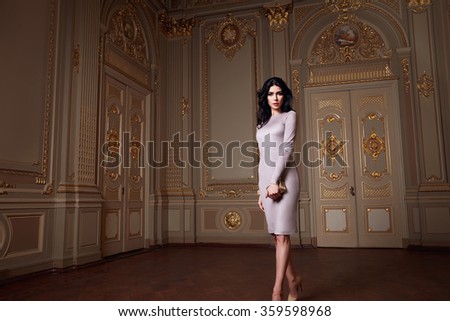 Beautiful sexy woman in elegant dress fashionable autumn Collection of spring long brunette hair makeup tanned slim body figure accessories interior luxury castle gold monogram baroque palace of Queen