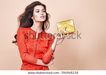 Glamour beautiful sexy brunette women, looks like a model, wearing evening make up in short red dress with small yellow bag in hands in fashion pose with amazing figure, perfect shape girl hairdo