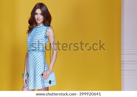 Glamour beautiful sexy brunette women, style look model wear short blue dress with small lather bag in hands in fashion pose with amazing figure, perfect shape girl hairstyle long legs make up party.
