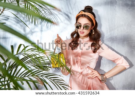 Sexy beauty woman in beige silk dress luxury chic fashion gold sunglasses brand hand bag trendy hat jewelry style for party date glamour pose summer palm clothes collection brunette hair