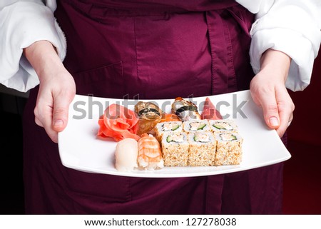 chief cook holding plate with sushi and sushi roll