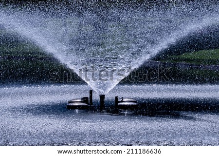 Water stream splashing on ground, Fountain,Water drops watering in arch curve shape. Closeup, shallow DOF