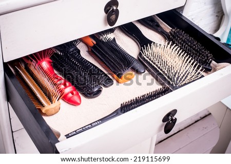 Barber's chair beside open draw of hair products, scissors and hairbrushes in salon, overhead view