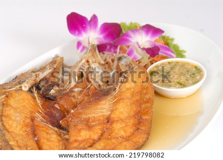 Deep Fried Tilapia fish fried with sauce spicy appetizing food on white plate in studio,Fish dish - deep fried fish with vegetables on white dish