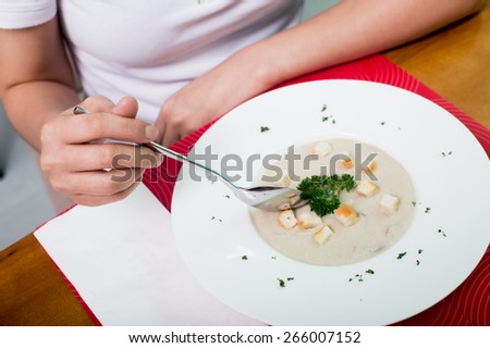 For mushroom soup, bowl on a table with mushroom soup and a spoon hovering above