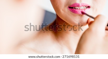 Makeup artist applying lipstick,Part of attractive woman\'s face with fashion red lips makeup