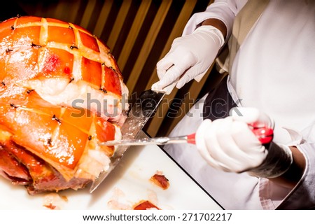 butcher\'s hand while fast cuts a piece of raw ham, cut ham