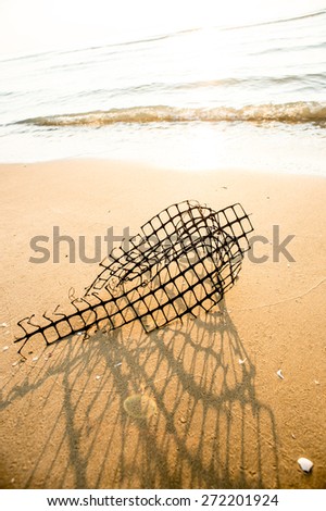 Steel wire on the beach,A fish trap entangled in kelp washes ashore on the beach